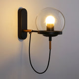 Black globe wall sconce lit warmly against a plain pale wall