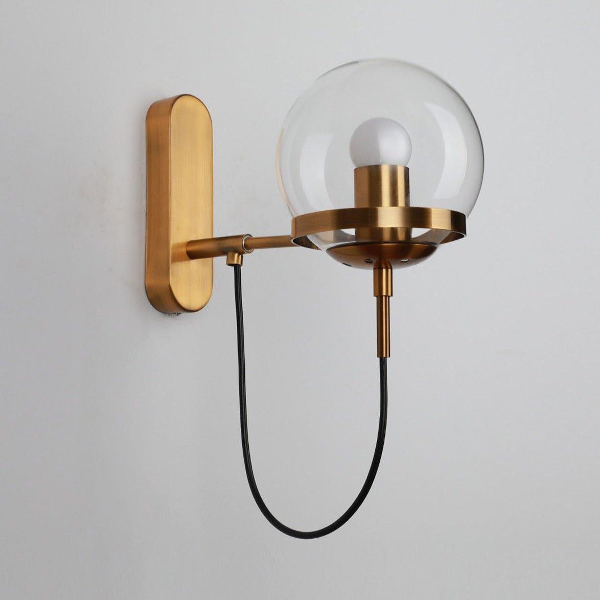Brass globe wall sconce shown unlit against a white background