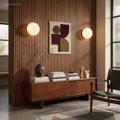 Two globe wall sconces flanking abstract art on a walnut slat wall