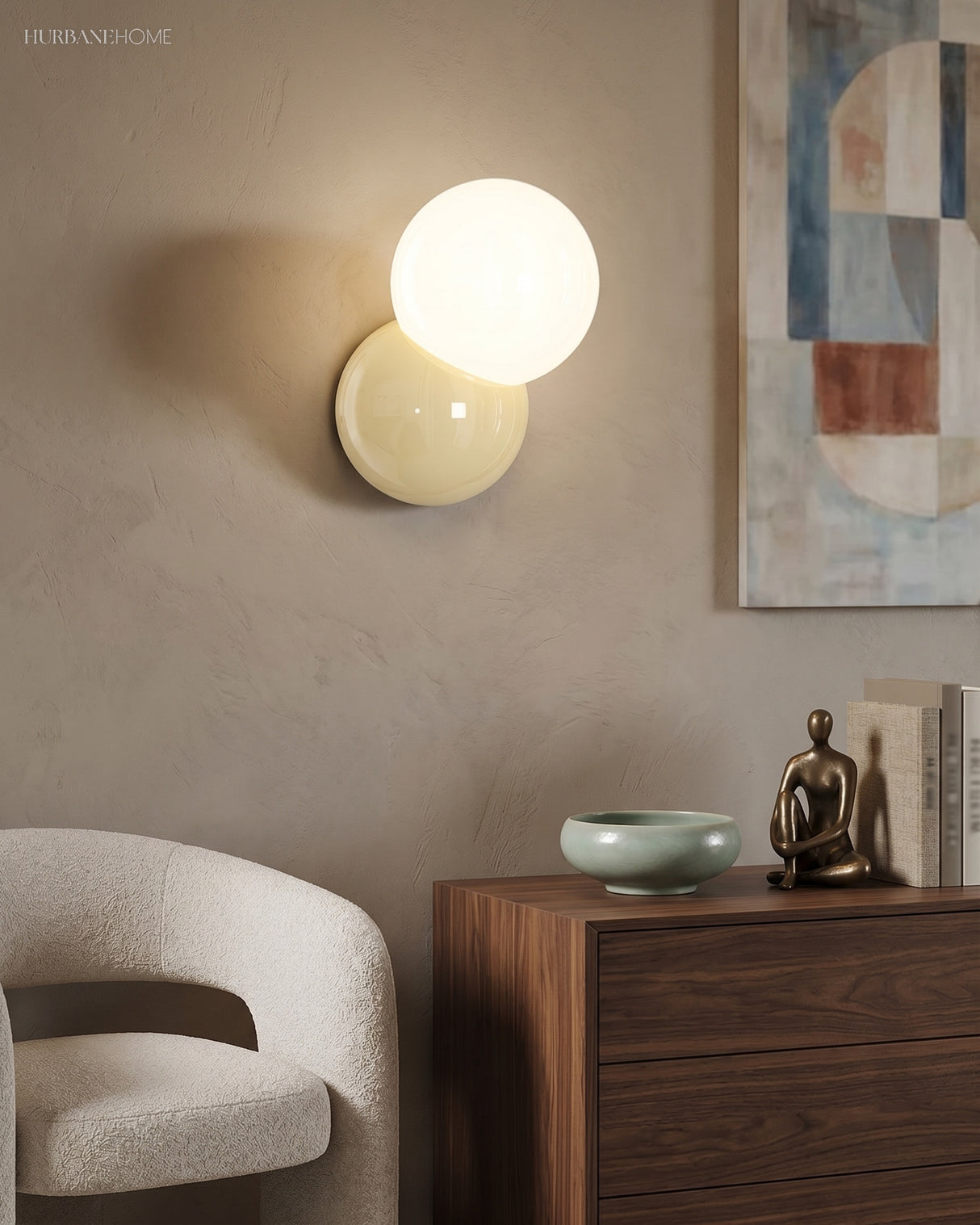 Wall sconce with an opal globe lit above a walnut sideboard and a boucle chair