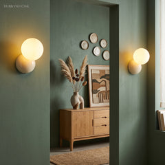 Pair of globe wall sconces either side of a doorway in a dark green hallway