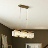 Close view of a gold three light pendant with faceted glass cube shades