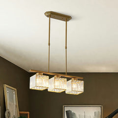 Close view of a gold three light pendant with faceted glass cube shades