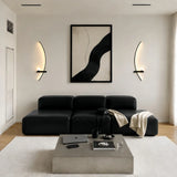 Gold arc wall sconce with a lit frosted globe on a neutral wall