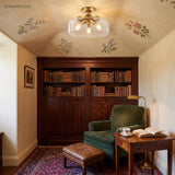 Gold clear-glass semi flush mount ceiling light in a floral reading nook
