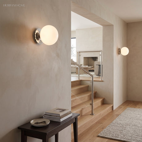 White globe sconce with chrome scalloped plate beside a staircase