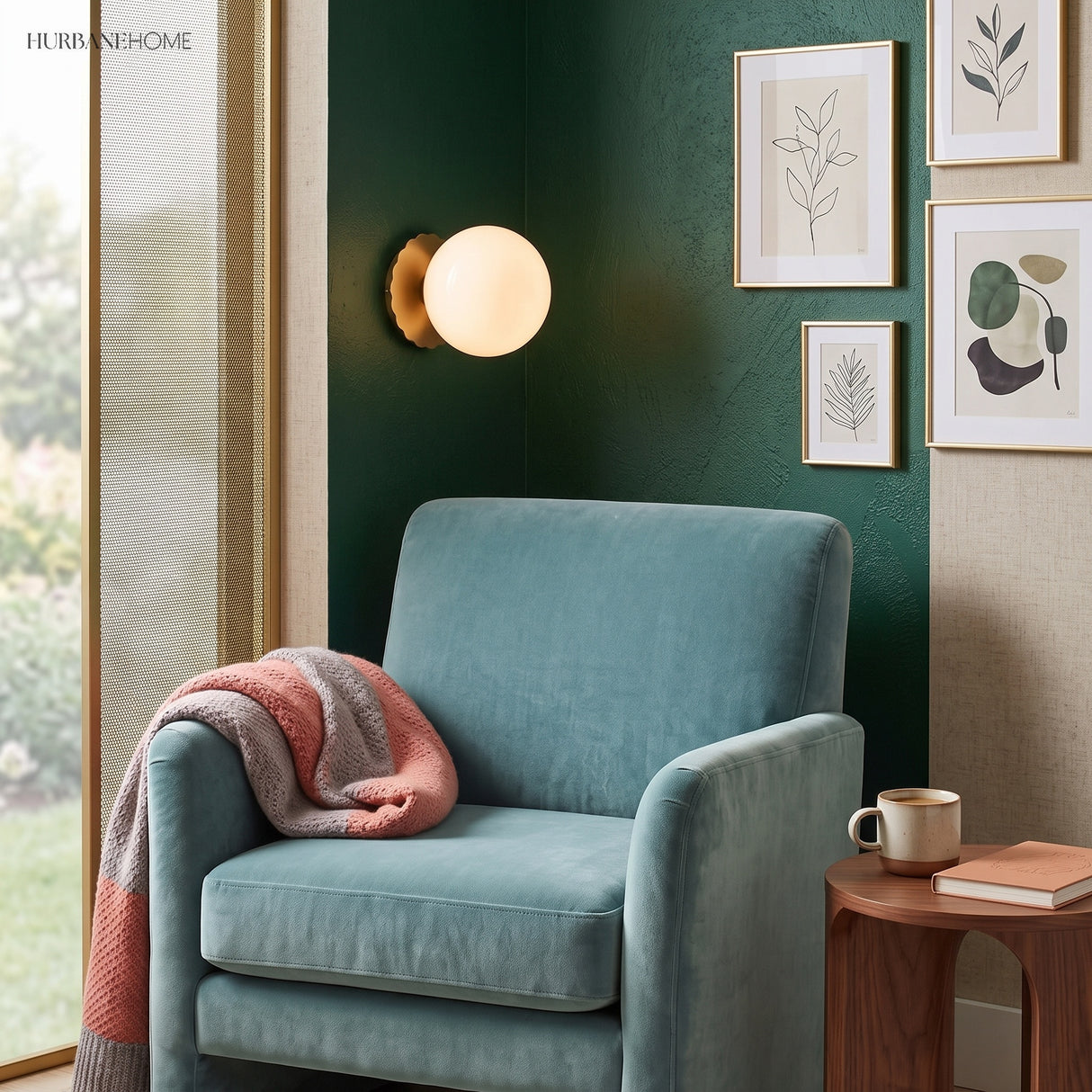 Globe wall sconce on green wall above a teal armchair and prints