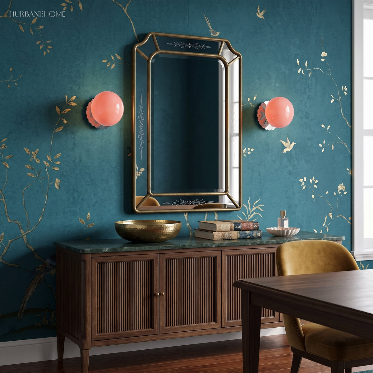 Pair of coral globe sconces beside a mirror on teal wallpaper