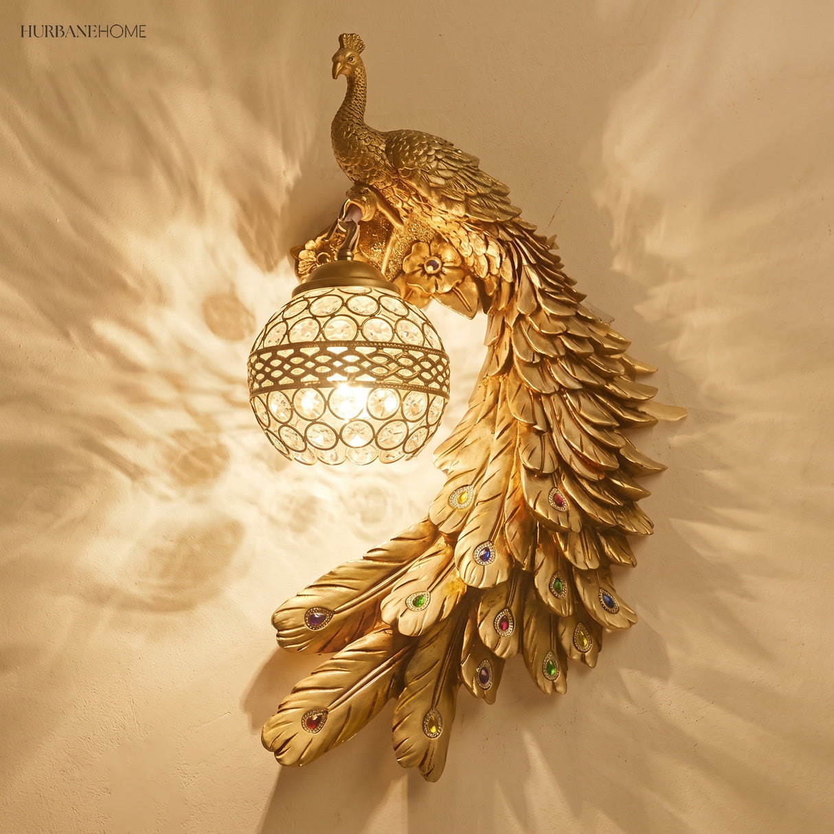 Gold peacock wall sconce glowing warmly against a plain beige interior wall