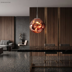 Rose gold molten pendant light hanging low over a dark stone dining table