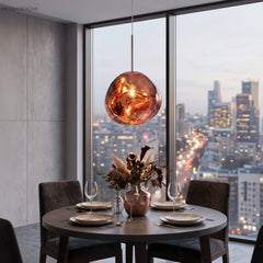 Copper toned pendant above a round dining table set against a night city view