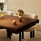 Gold dome lamp on a dark timber dining table with cream boucle chairs