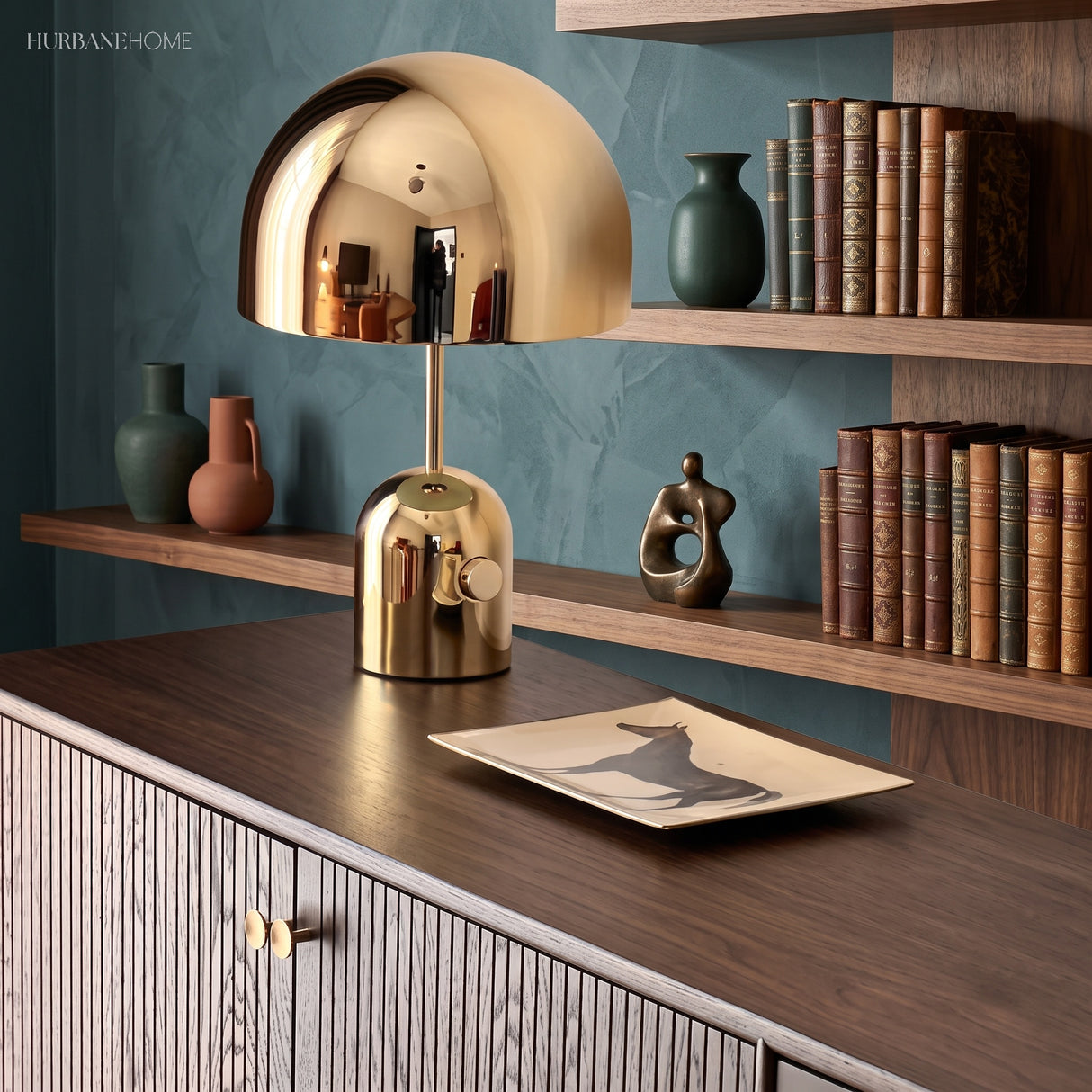 Gold dome table lamp on a fluted sideboard against a teal shelved wall