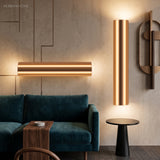 Two gold tube sconces lit above a green sofa and side table