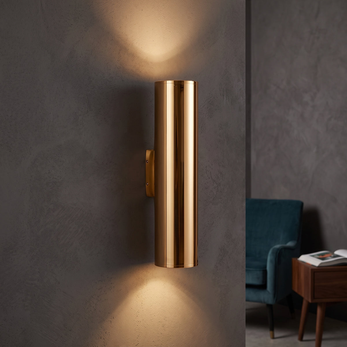 Gold tube sconce lighting a grey wall above and below