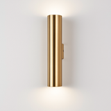 Gold tube sconce lit and shown against a plain background