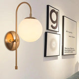 Gold globe wall sconce beside a small gallery wall of prints