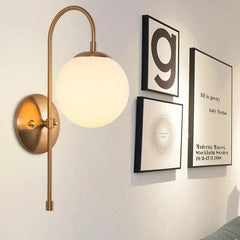 Gold globe wall sconce beside a small gallery wall of prints