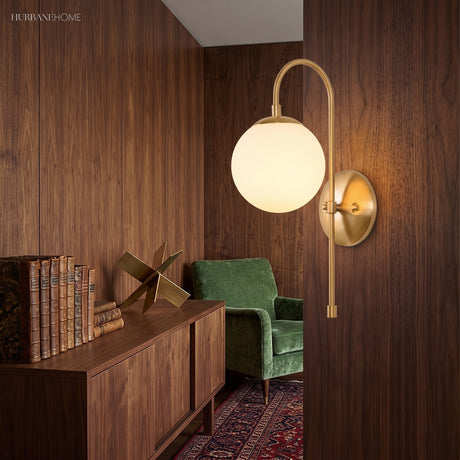 Gold globe sconce lit on a walnut panelled wall above a sideboard