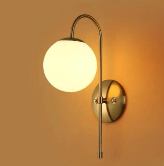 Gold arched arm sconce lit against a warm ochre wall