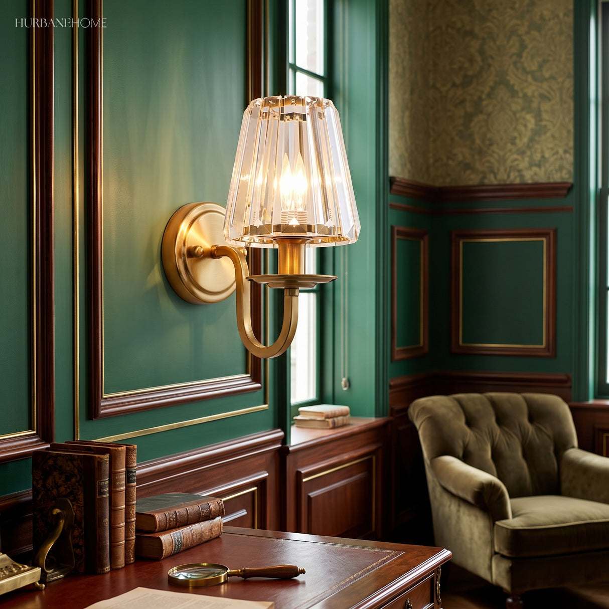Gold sconce lit on a deep green panelled study wall