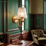 Gold sconce lit on a deep green panelled study wall