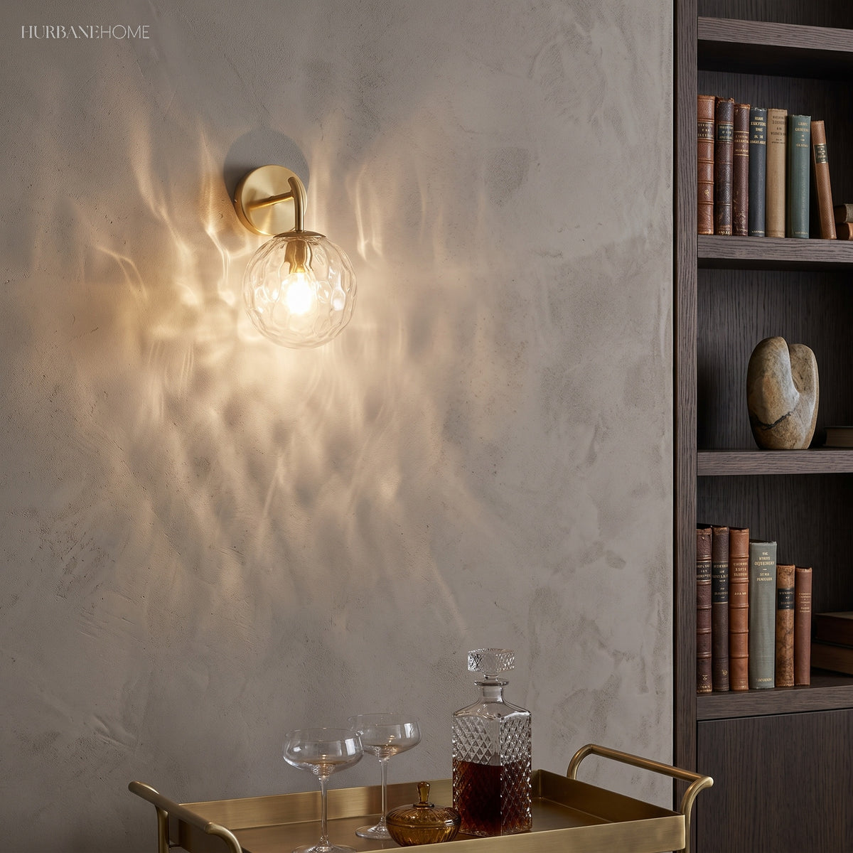 Gold globe sconce lit above a bar cart in a book lined room