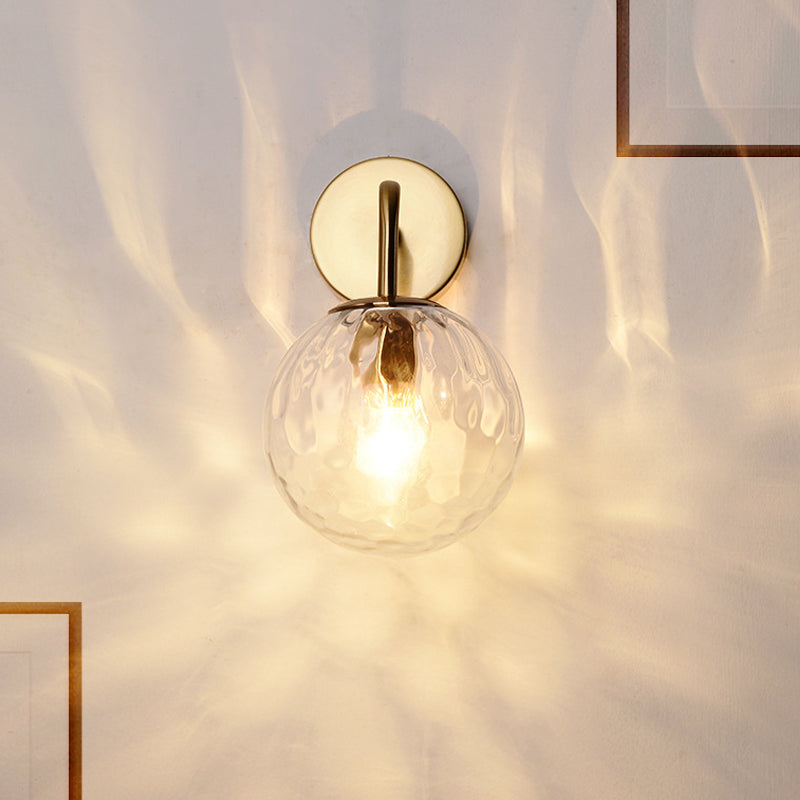 Rippled globe sconce lit warm next to a thin brass picture frame