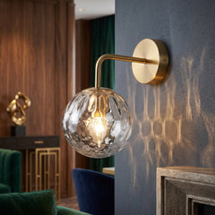 Gold sconce with a rippled glass globe on a deep blue wall
