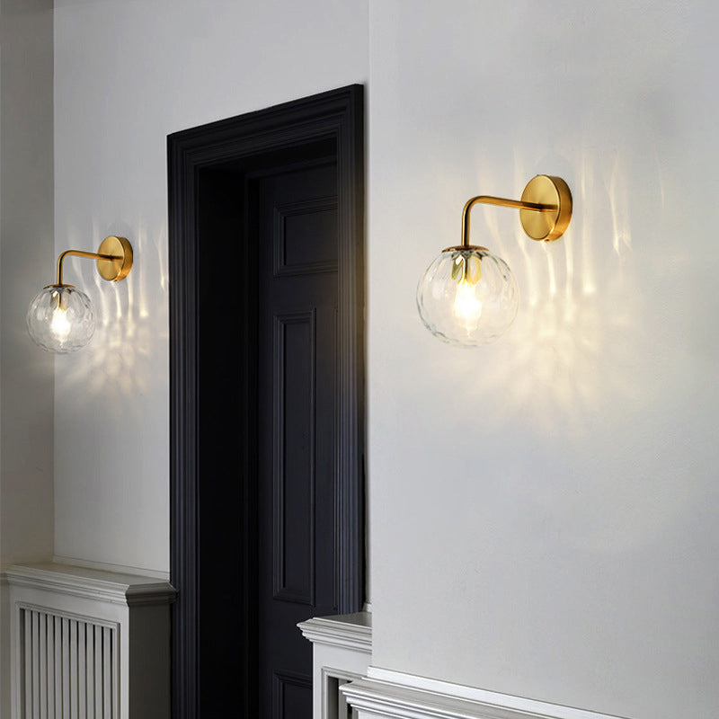 Two gold globe sconces flanking a dark doorway in a white hall