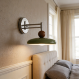 Green disc wall sconce angled to direct light downward for reading