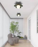 Two green petal flower ceiling lights above a bright hallway with a potted tree