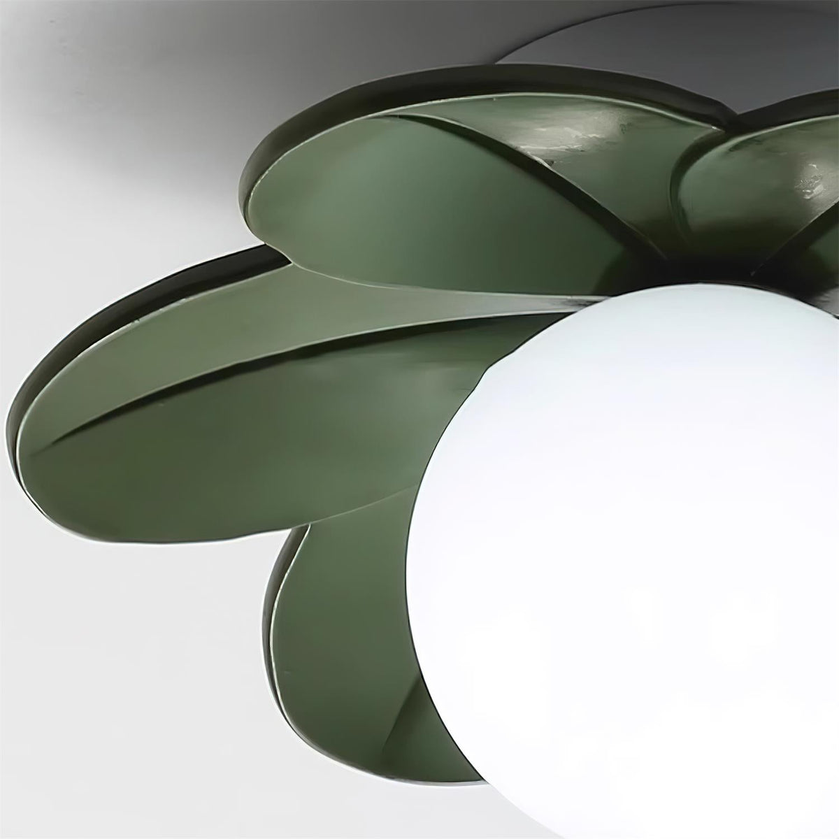 Detail of the green petals curving around the white glass globe of the fitting
