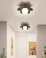 Green flower ceiling lights above a pale landing with framed prints and a doorway