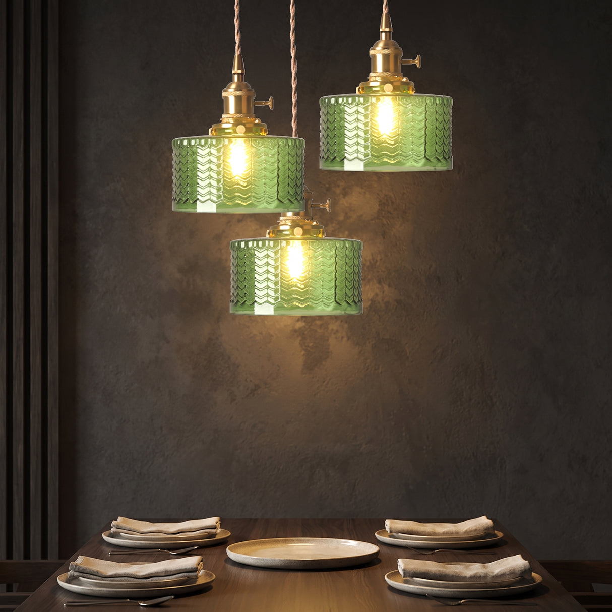 Cluster of three green glass cylinder pendants against a dark plaster wall