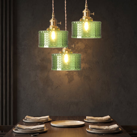 Cluster of three green glass cylinder pendants against a dark plaster wall