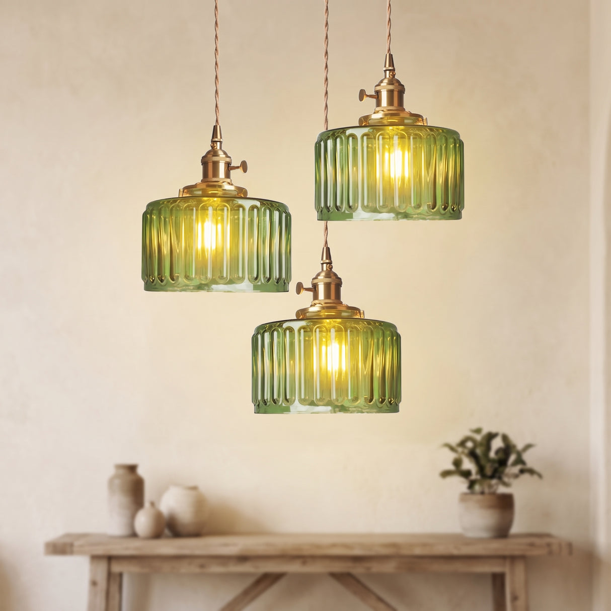 Three green glass pendants at staggered drops above a pale console table