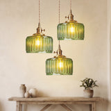 Three green glass pendants at staggered drops above a pale console table