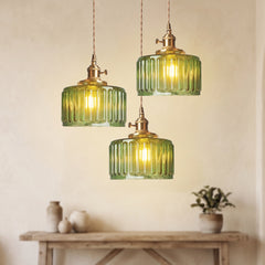 Three green glass pendants at staggered drops above a pale console table