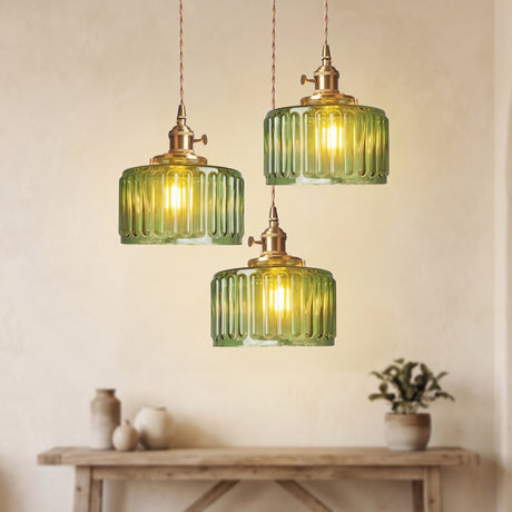 Three green glass pendants at staggered drops above a pale console table