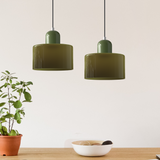 Two green glass pendant lights above a kitchen counter with a potted plant