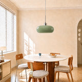 Green glass pendant light over a round table against a sunlit wall