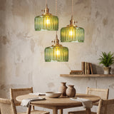 Three green fluted glass pendants clustered above a round oak dining table