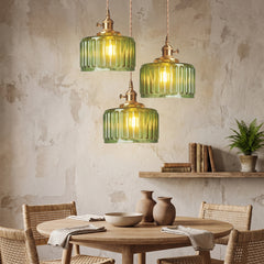 Three green fluted glass pendants clustered above a round oak dining table