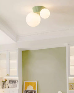 Green canopy globe light on a white ceiling above a green painted study wall