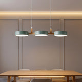 Sage green drum shades on a wood crossbar above a light oak dining table