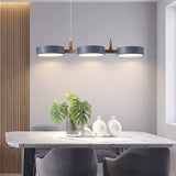 Three matching grey drum shades casting warm pools onto a marble dining table