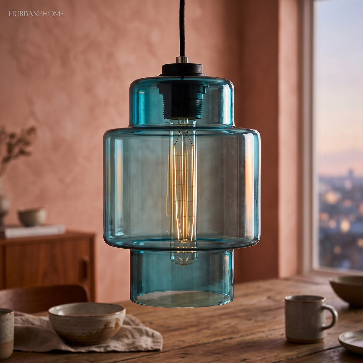 Blue stepped glass pendant lit against a terracotta plaster wall