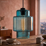 Blue stepped glass pendant lit against a terracotta plaster wall