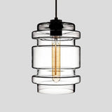 Clear ribbed glass pendant with stacked rings, lit against grey
